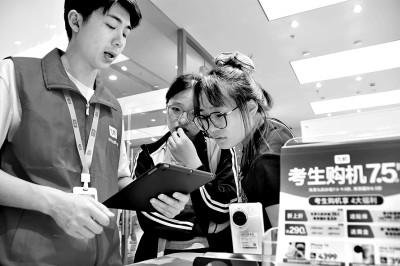 云南省蒙自市一店內(nèi)工作人員為今年高考考生講解手機(jī)“國補(bǔ)”政策。薛瑩瑩攝:光明圖片.jpg